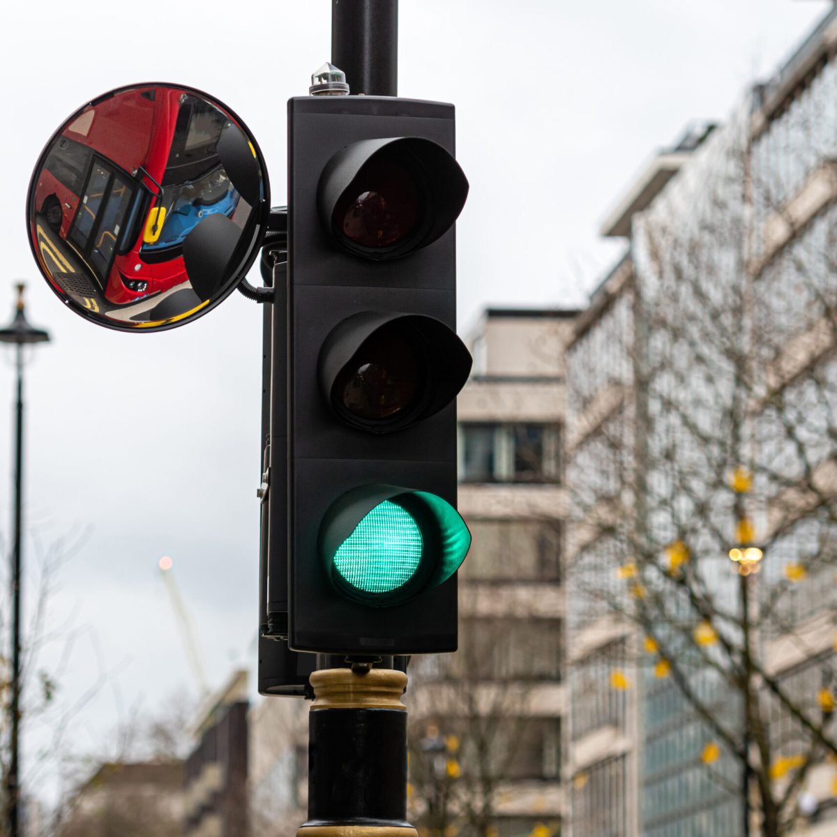 London, England, UK, Green Traffic Light Signal and Traffic Convex Mirror with the Reflection of the red bus